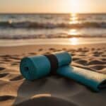 A serene beach at sunset, with a lone yoga mat laid out on the sand, facing the calm ocean waves